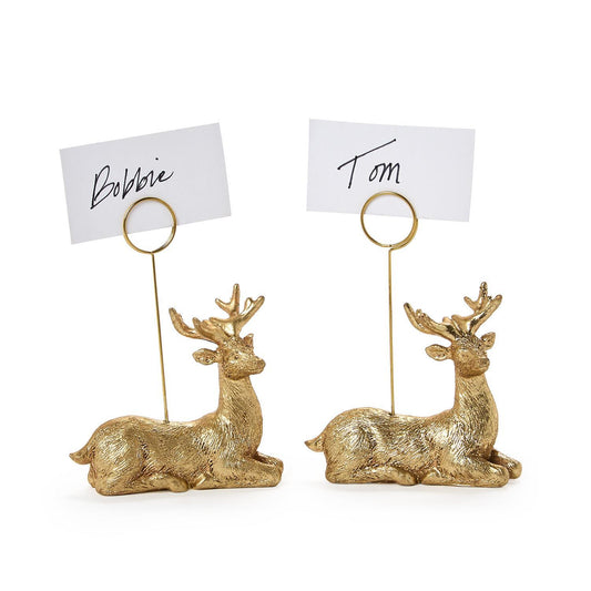 Two golden deer place card holders holding handwritten name cards