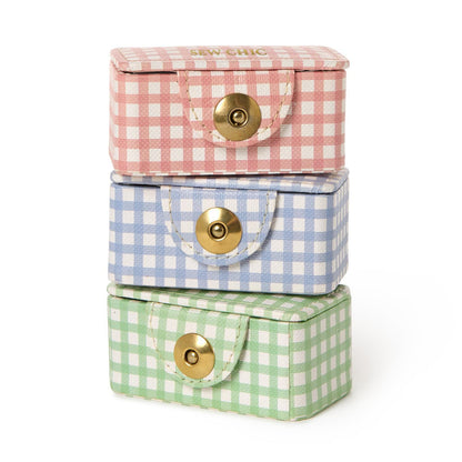 Three gingham mini sewing kit boxes stacked in pink, blue and green with gold snap closures