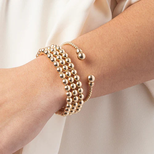 enewton Classic Gold 3mm Bead Cuff worn on the wrist stacked with gold beaded bracelets