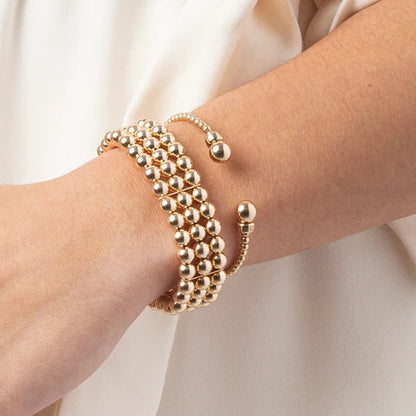 enewton Classic Gold 3mm Bead Cuff worn on the wrist stacked with gold beaded bracelets