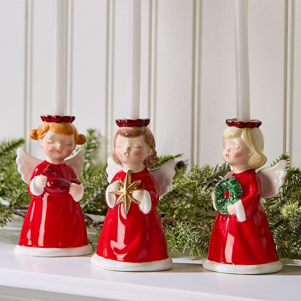 Christmas angel candleholders on a mantel with greenery
