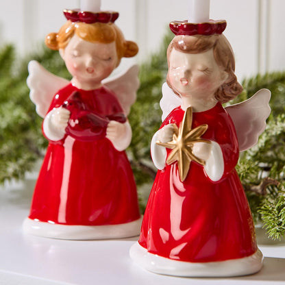 Close-up of angel candleholders holding a red cardinal and a gold star