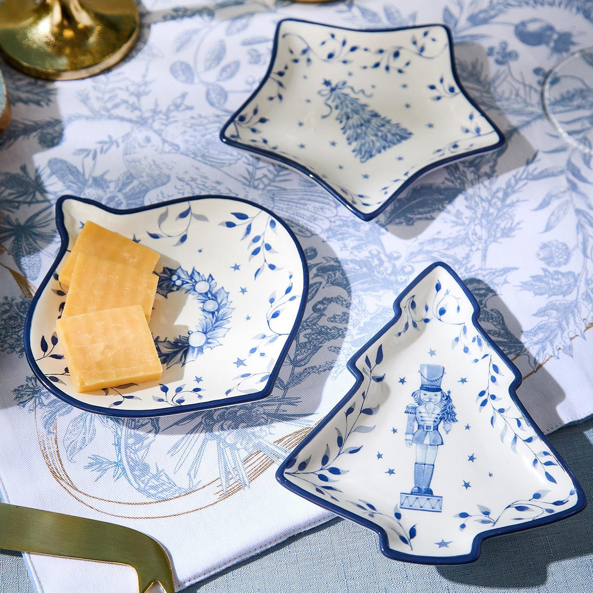 Blue and white Christmas tidbit dishes holding cheese and crackers on a holiday table