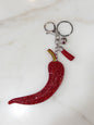 Red glittery keychain with a small attached item on a light marble background