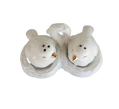 Two white ceramic bird-shaped salt and pepper shakers on a light surface.