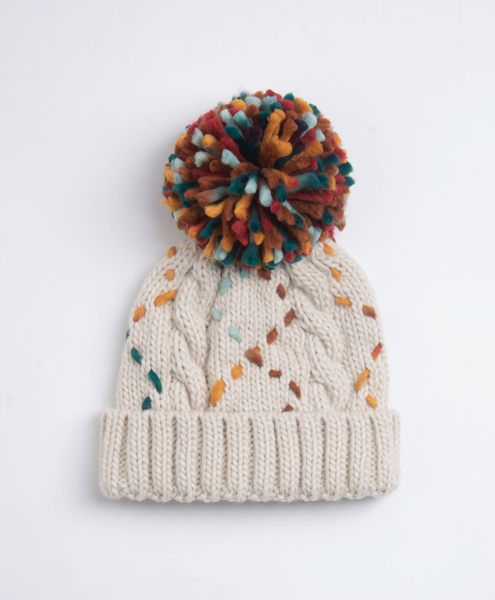 Cream cable knit pom pom beanie with colorful stitching