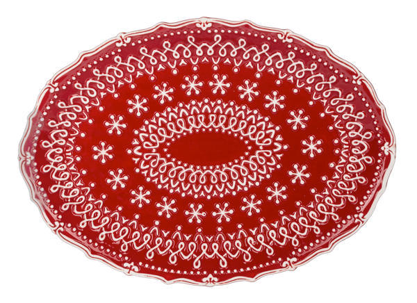 Oval red platter covered in raised white snowflake lacework with a scalloped edge