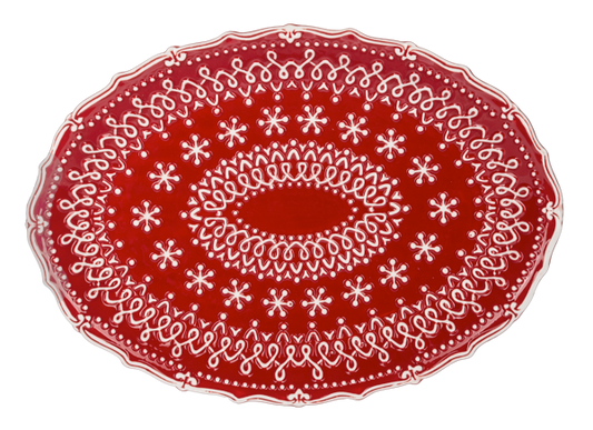 Oval red platter covered in raised white snowflake lacework with a scalloped edge